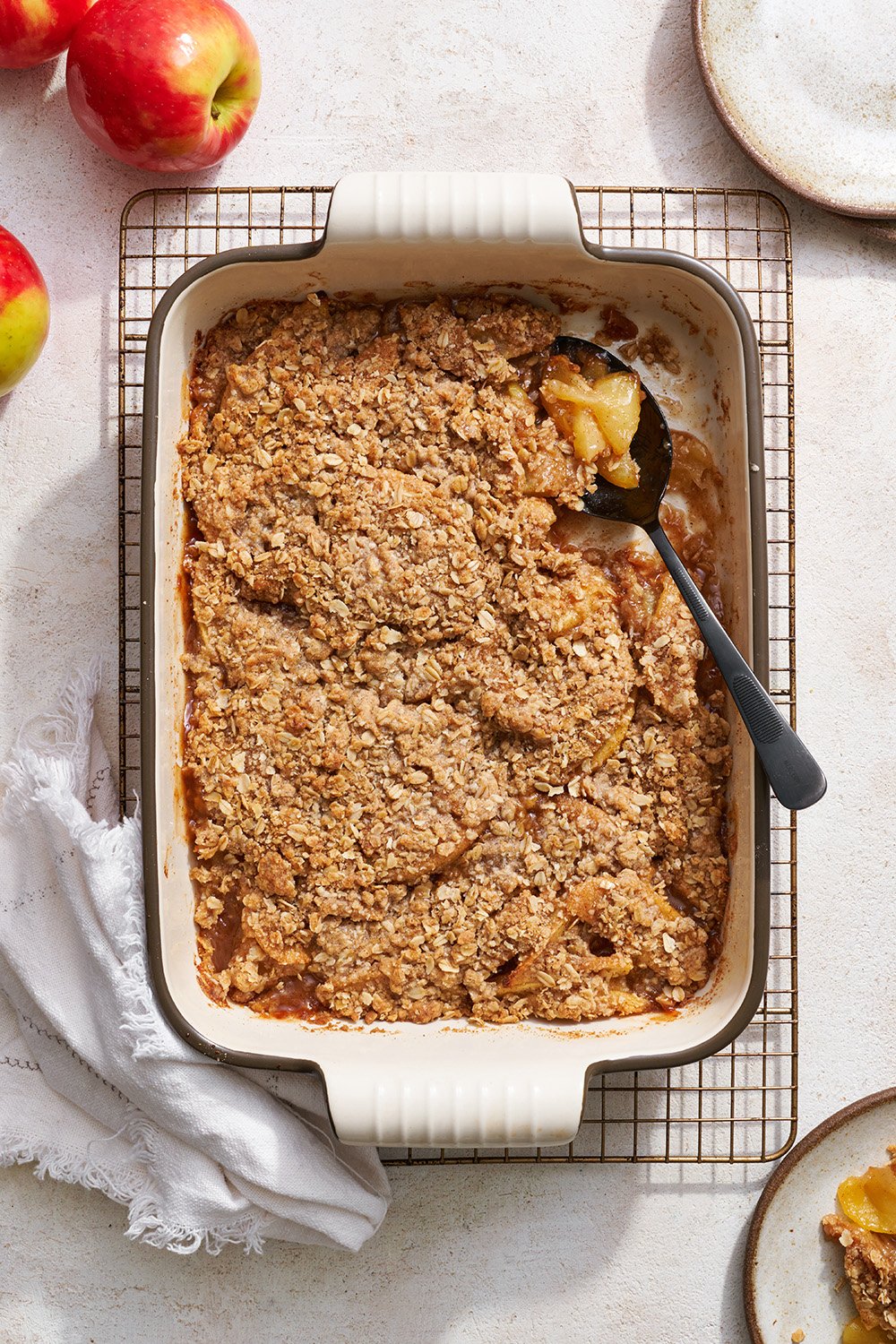 baked apple crisp in a 9x13-inch pan with a spoon to serve