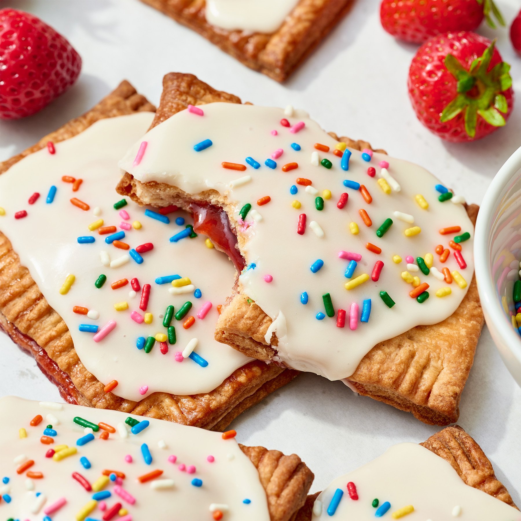 homemade strawberry pop tarts with strawberry filling, vanilla icing, and sprinkles