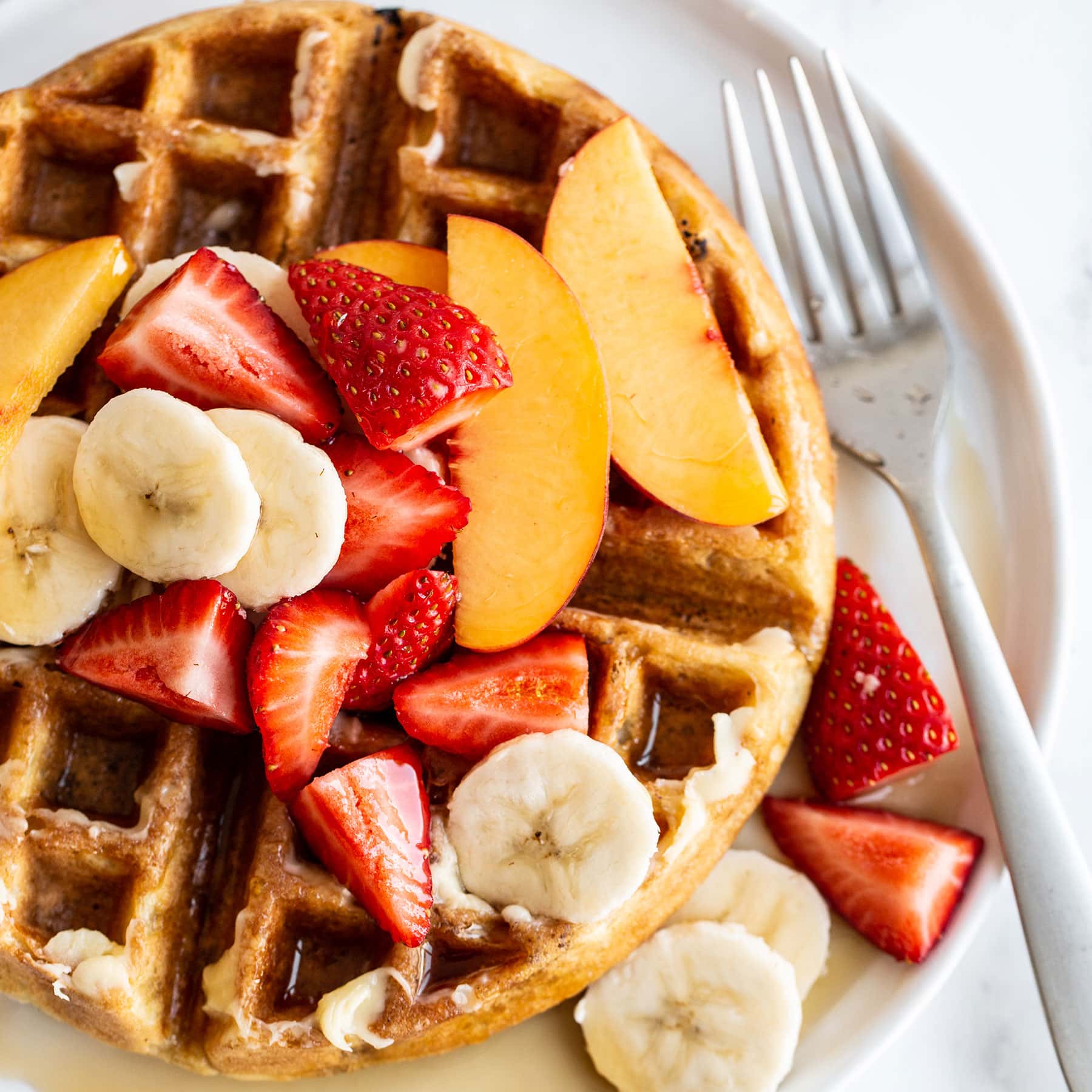 Homemade Belgian waffle on a plate with syrup and fresh fruit