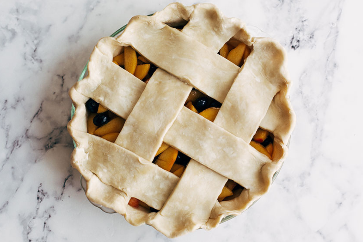 an unbaked blueberry peach pie topped with a lattice pie crust.