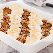 sweet potato casserole, half with brown sugar pecan topping and the other half with marshmallow topping, attractively arranged into rows of topping, inside a white ceramic casserole dish.